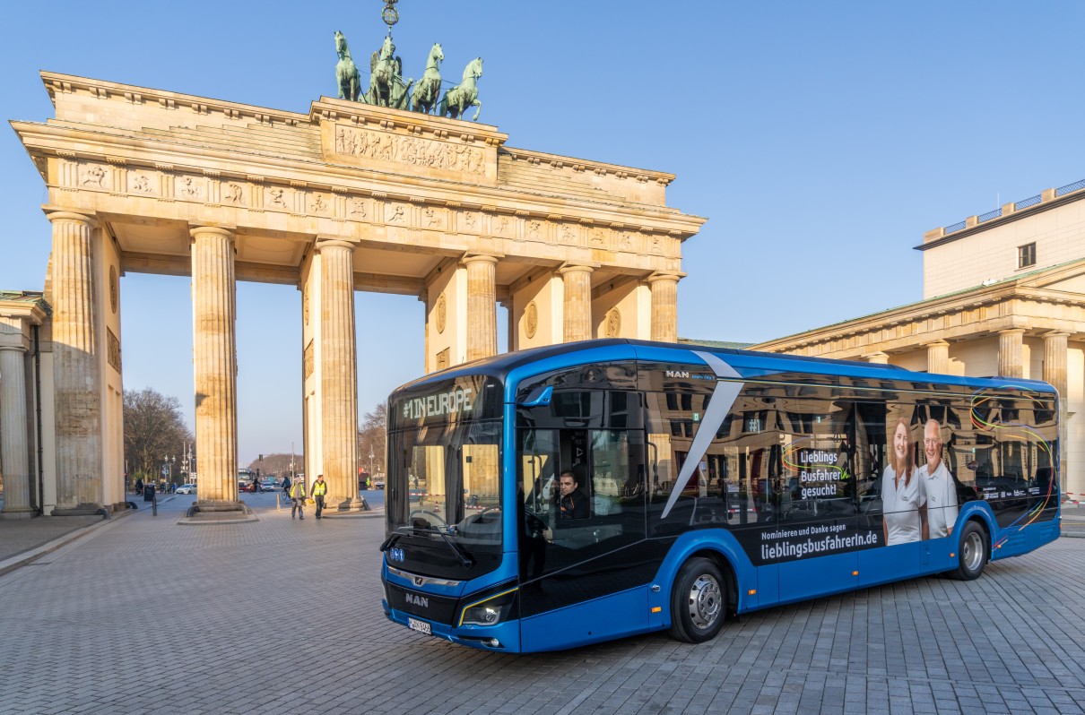 Das Kampagnenmotiv zum Wettbewerb „LieblingsbusfahrerIn“ auf einem modernen Stadtbus vor dem Brandenburger Tor in Berlin. 