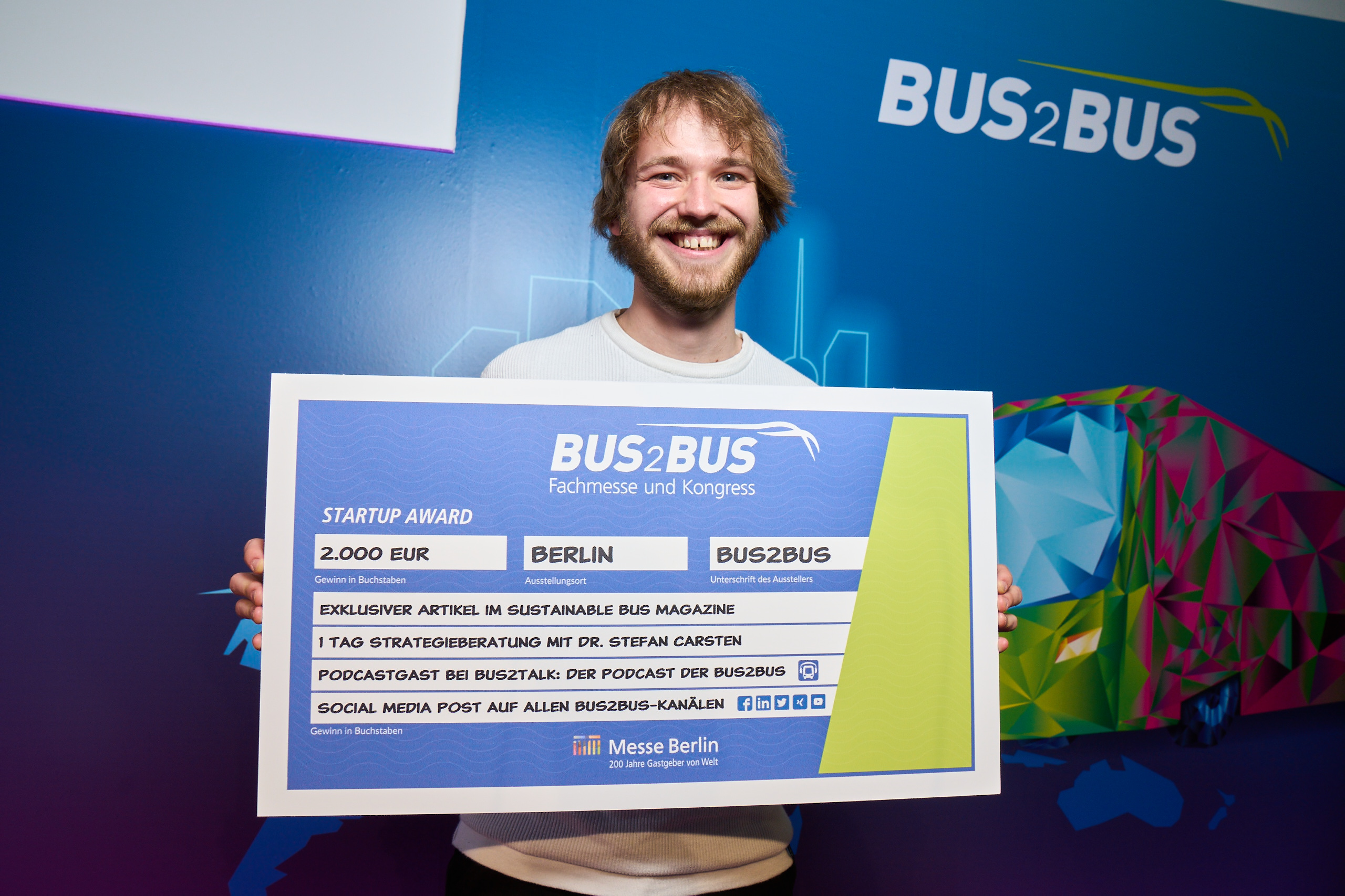 Das Bild zeigt die Preisverleihung des Startup Awards 2022 und den Gewinner Ben Gallmeister von Vesputi, der einen Scheck in den Händen hält.